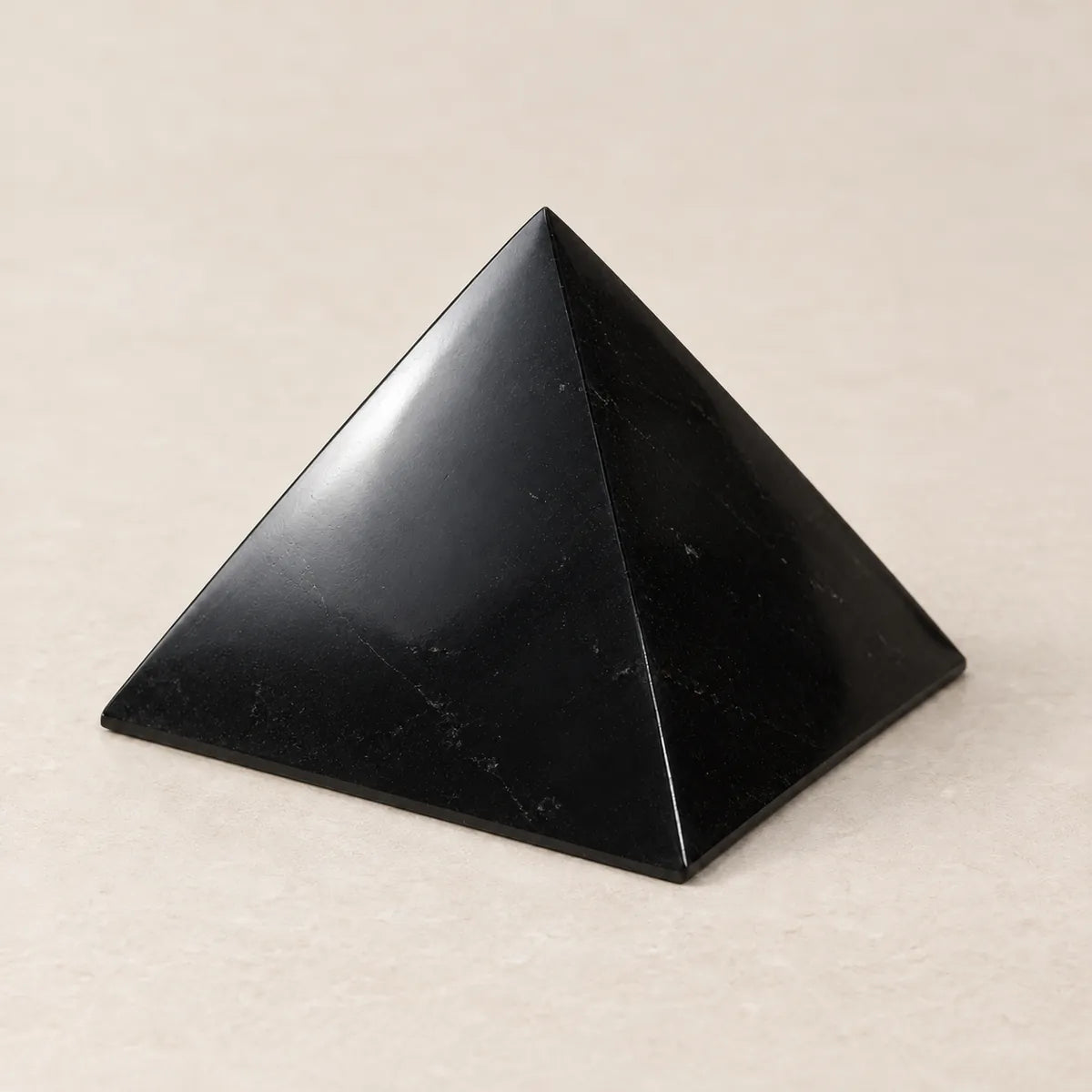 Piramide lucidata in shungite, su fondo chiaro