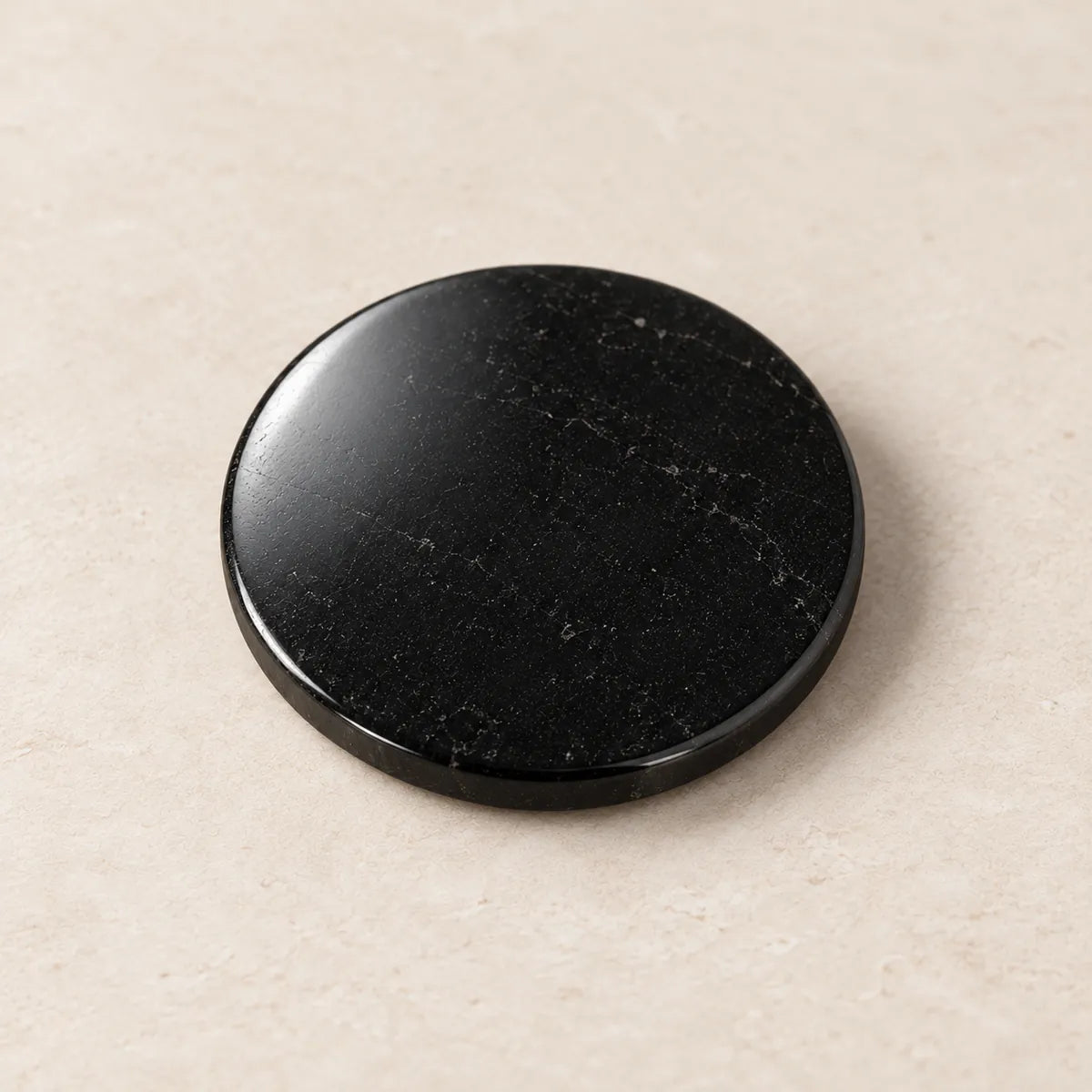 Disco circolare lucidato in shungite, 20 mm, su fondo chiaro