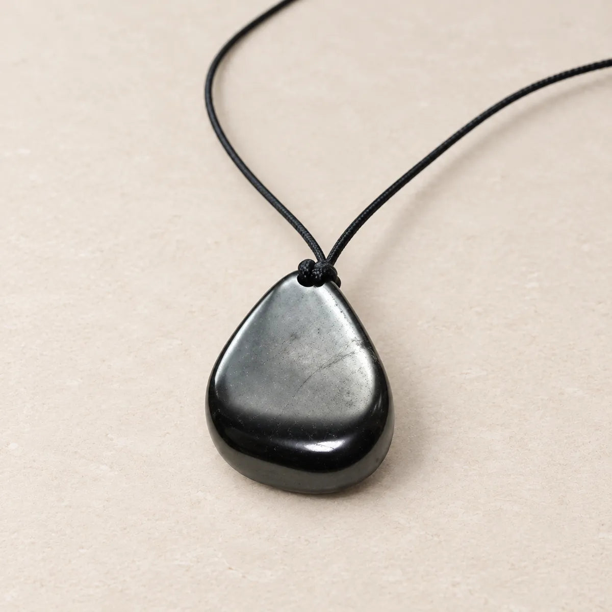 Pendente burattato in shungite, su fondo chiaro