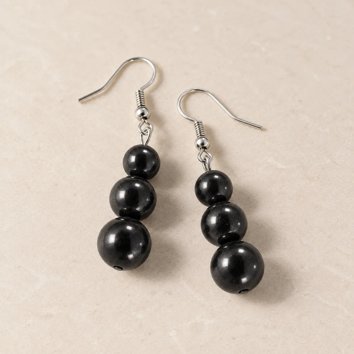 Orecchini con tre perline in shungite, su fondo chiaro
