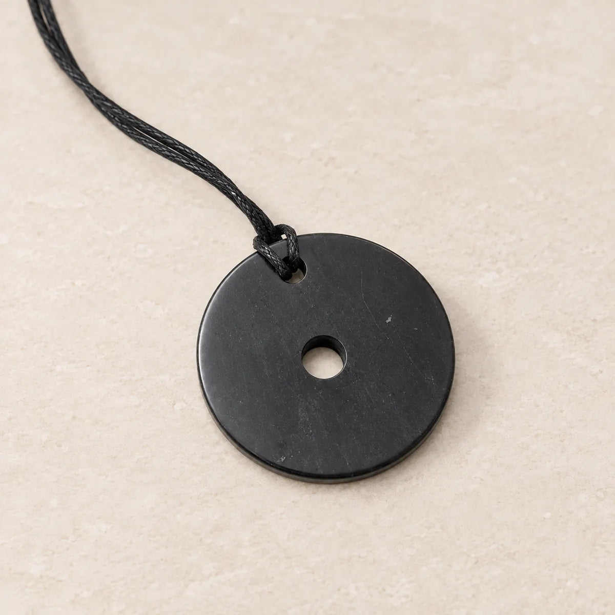 Pendente con foro in shungite, su fondo chiaro