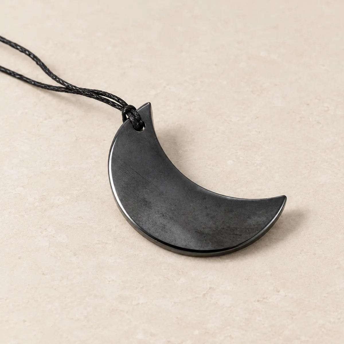 Pendente mezzaluna in shungite, su fondo chiaro
