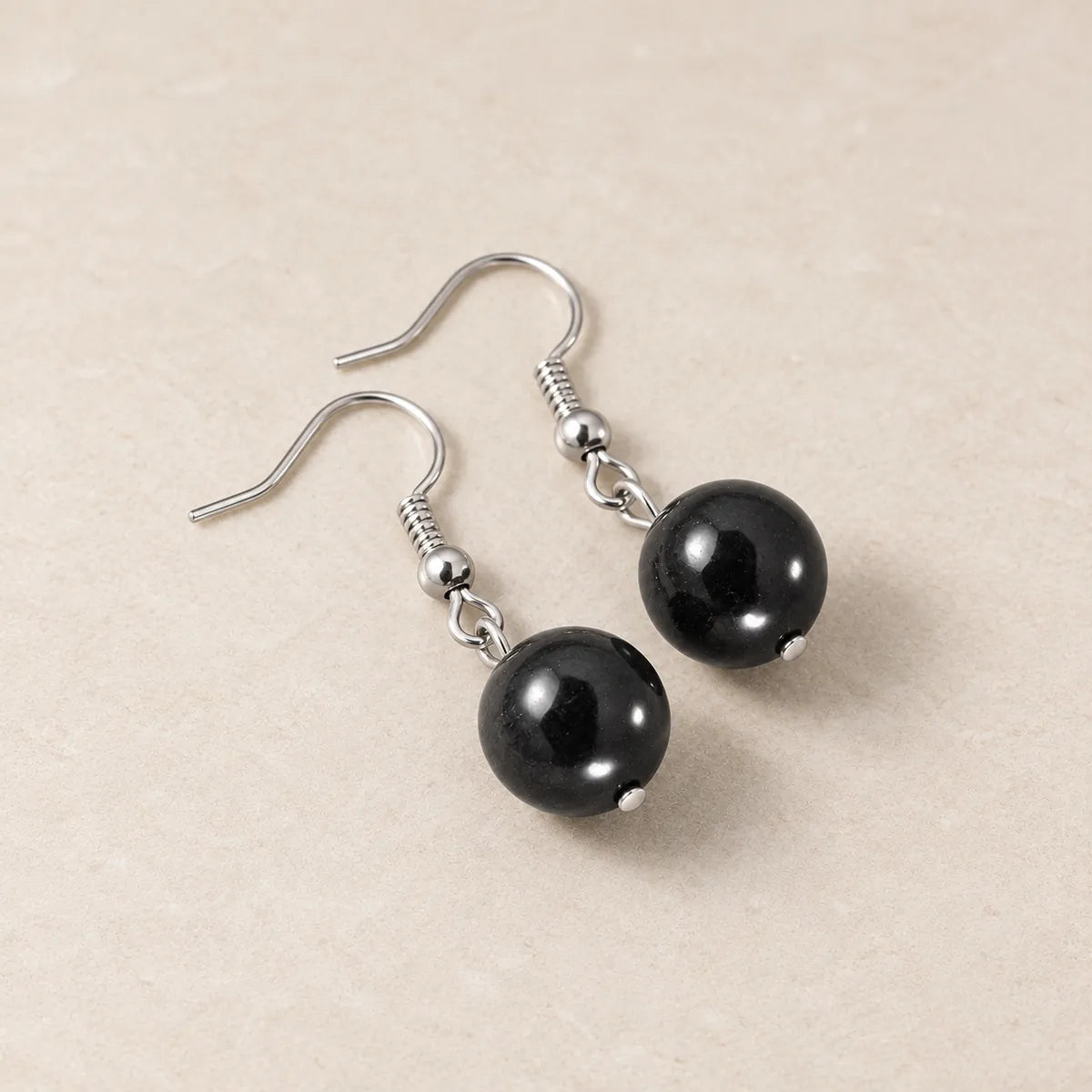 Orecchini con una perlina in shungite, su fondo chiaro