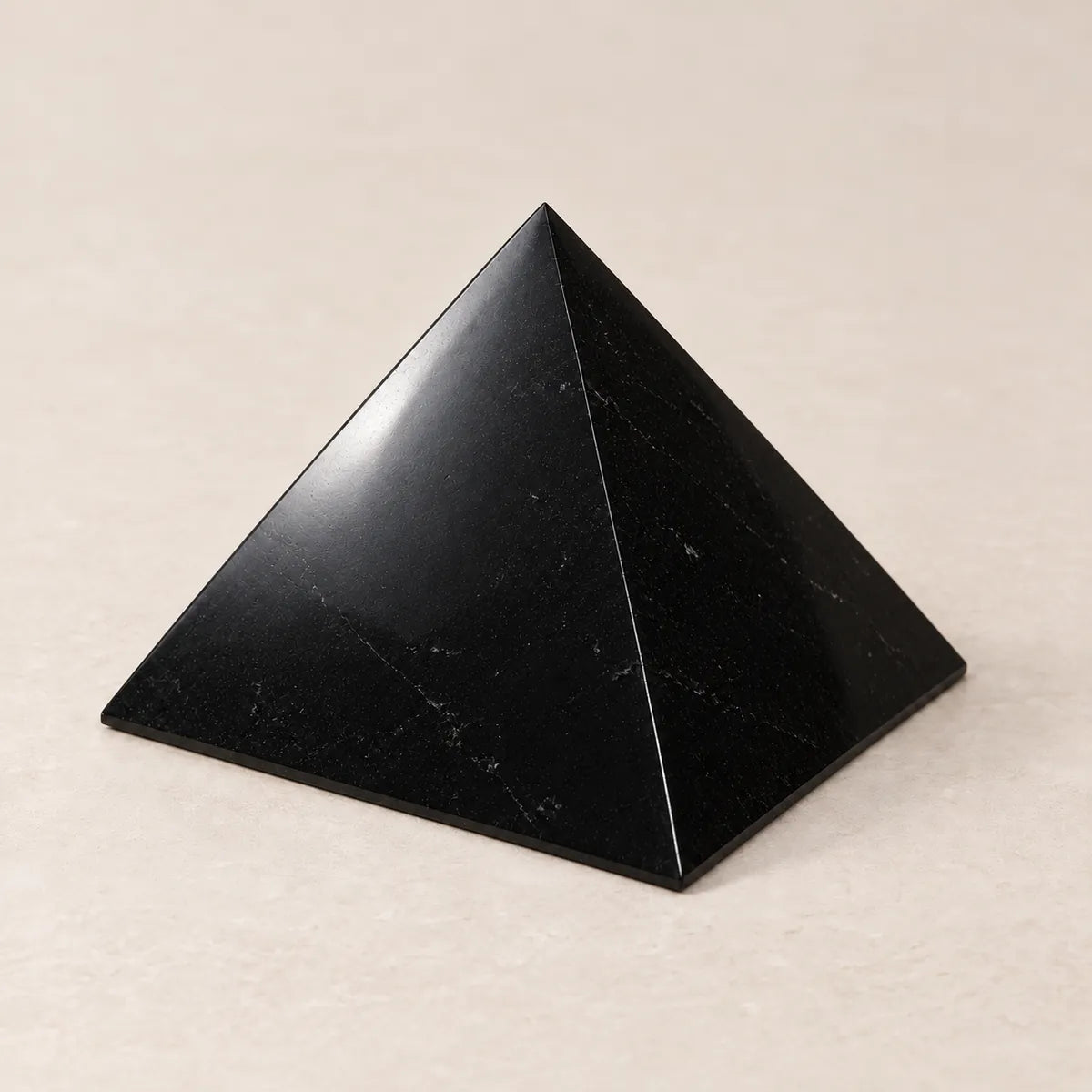 Piramide lucidata in shungite, su fondo chiaro