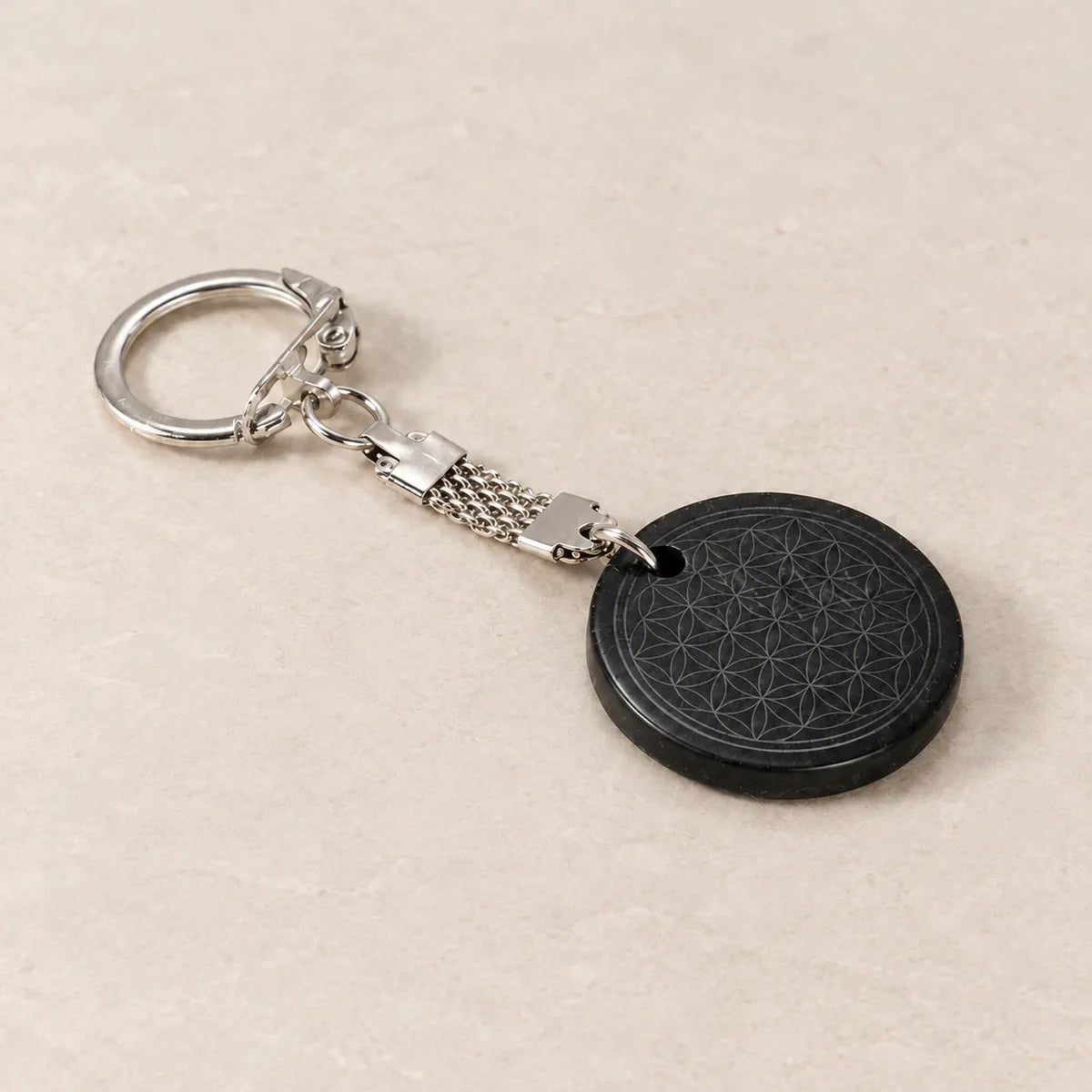 Portachiavi cerchio 30 mm con Fiore della Vita in shungite, su fondo chiaro