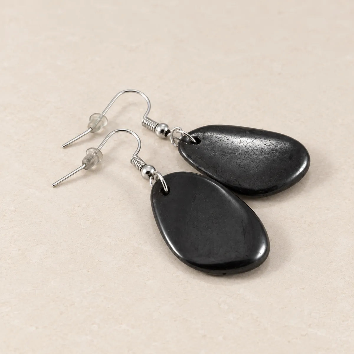 Orecchini burattati in shungite, su fondo chiaro