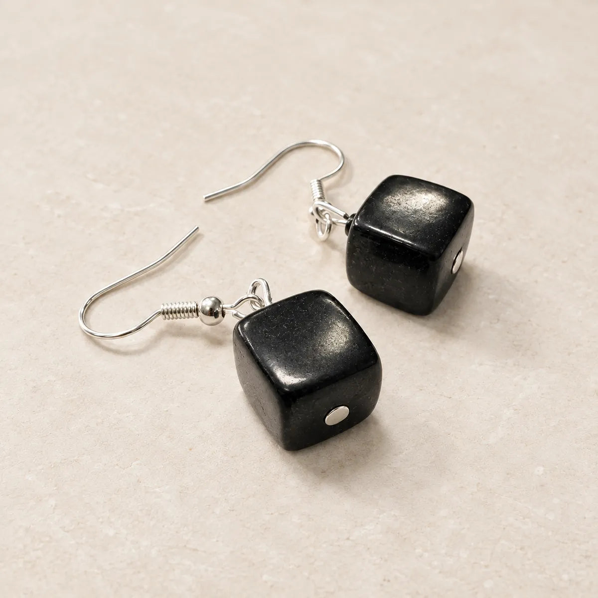 Orecchini cubo lucidato in shungite, su fondo chiaro