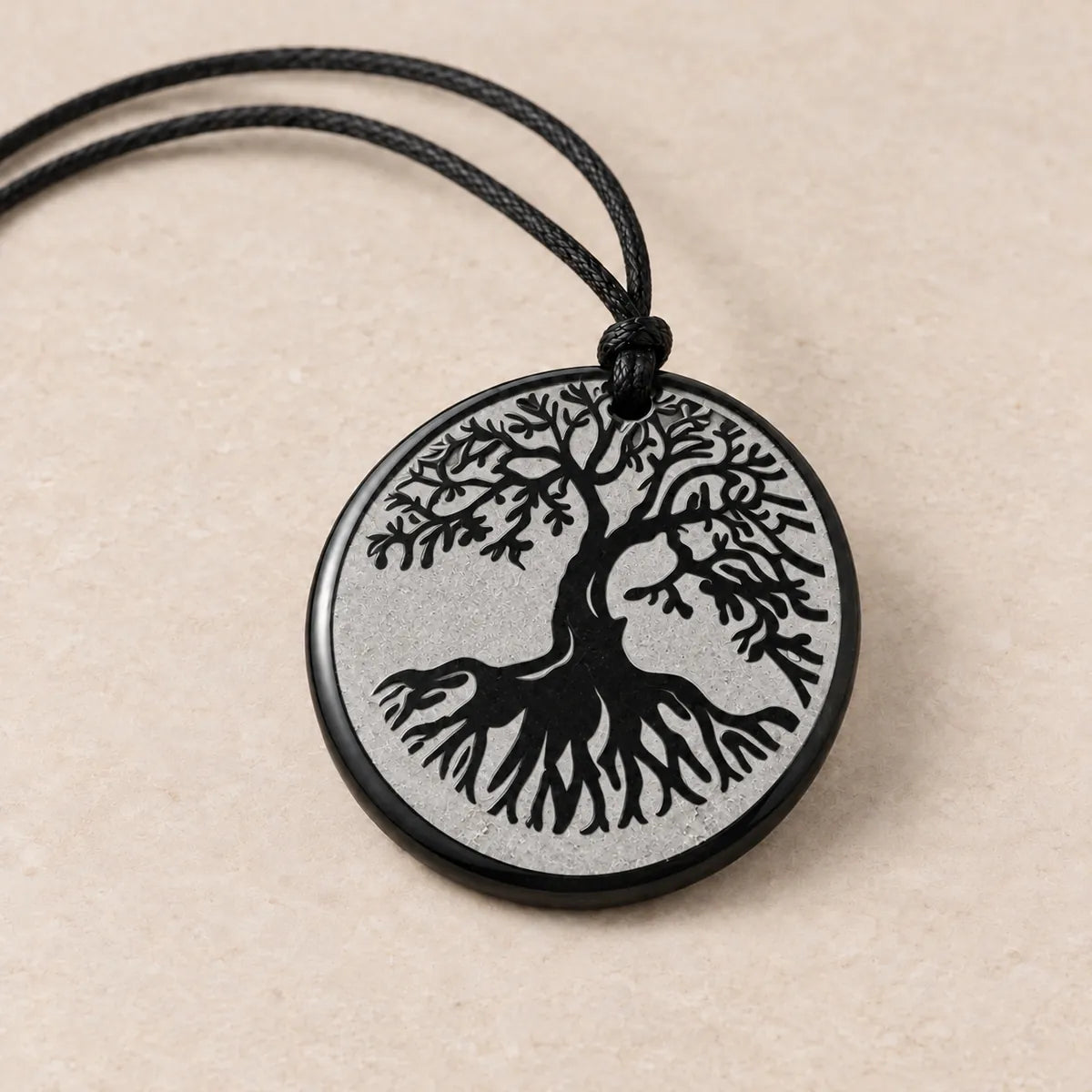 Pendente cerchio 30 mm inciso in shungite, Albero della Vita, su fondo chiaro