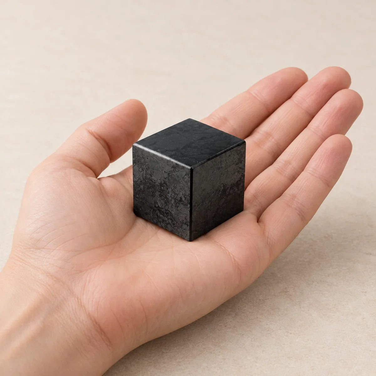 Cubo lucidato in shungite, tenuto in mano