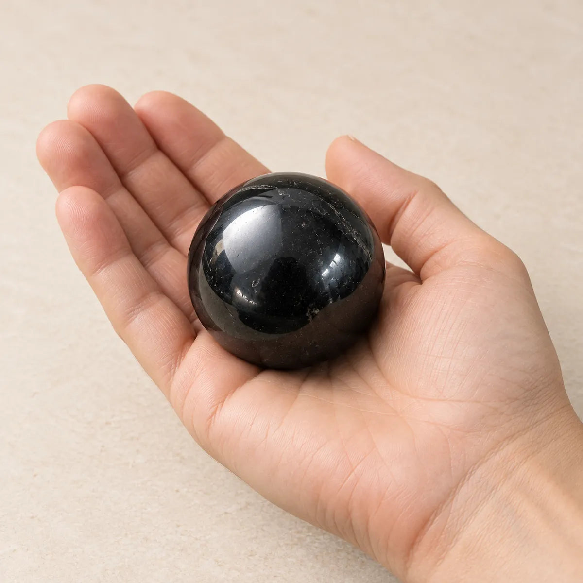 Sfera lucidata in shungite, tenuta in mano