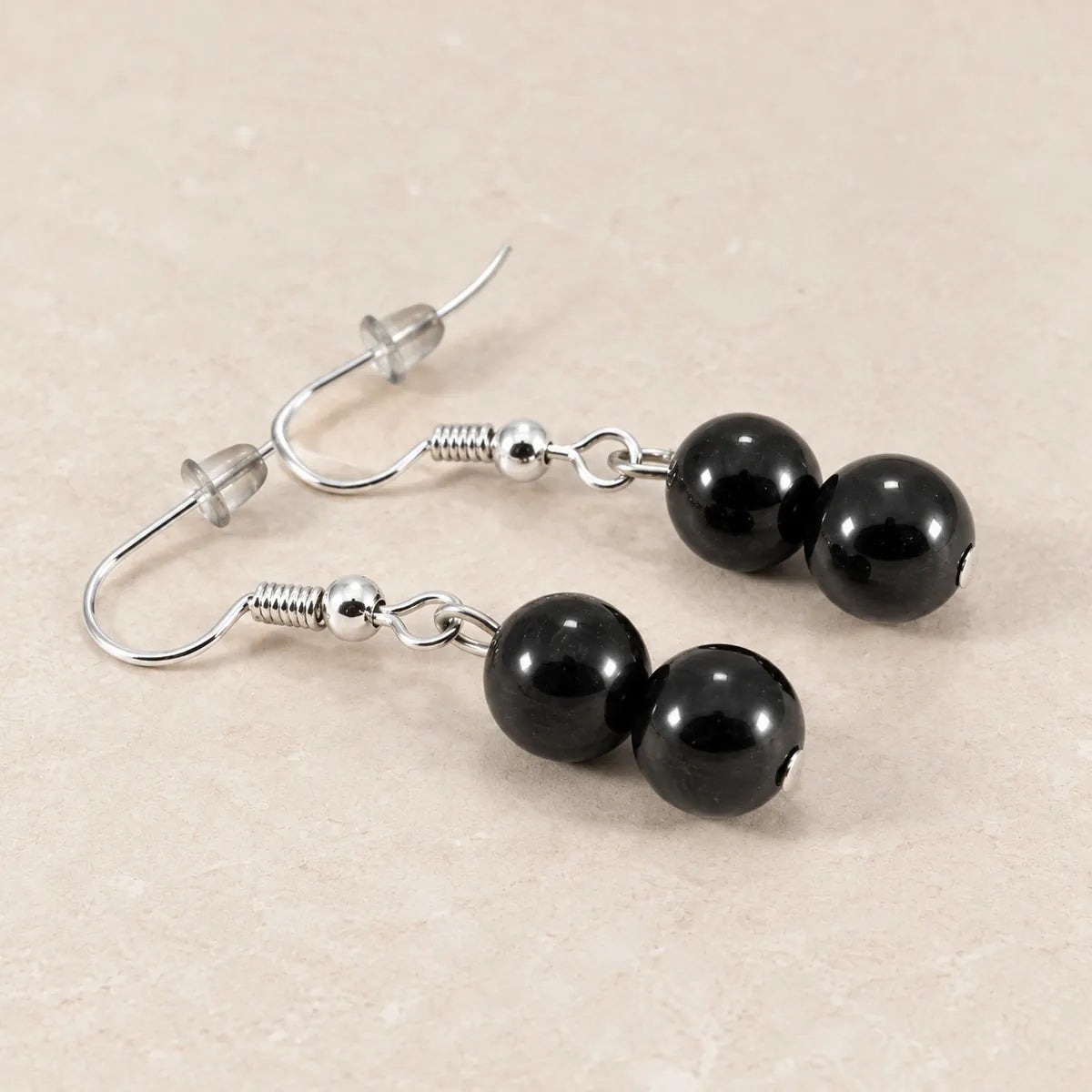 Orecchini con due perline in shungite, 10 mm + 12 mm, su fondo chiaro