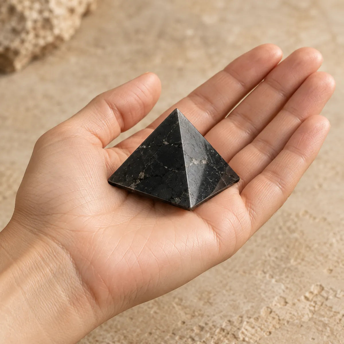 Piccola piramide di shungite appoggiata sul palmo di una mano