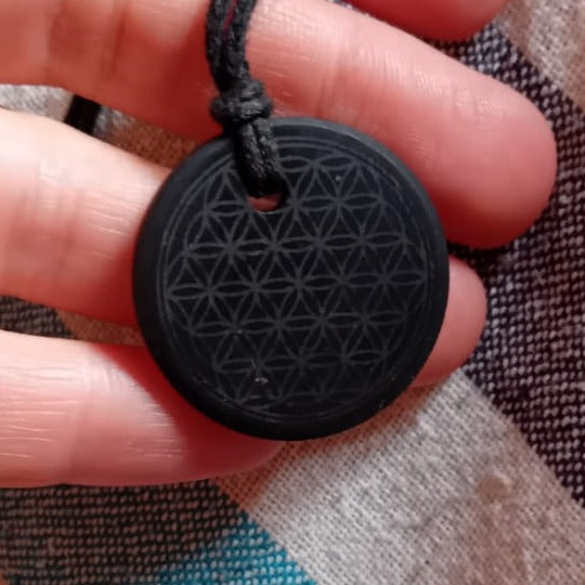 Il pendente col Fiore della Vita in shungite, in mano, col cordino nero