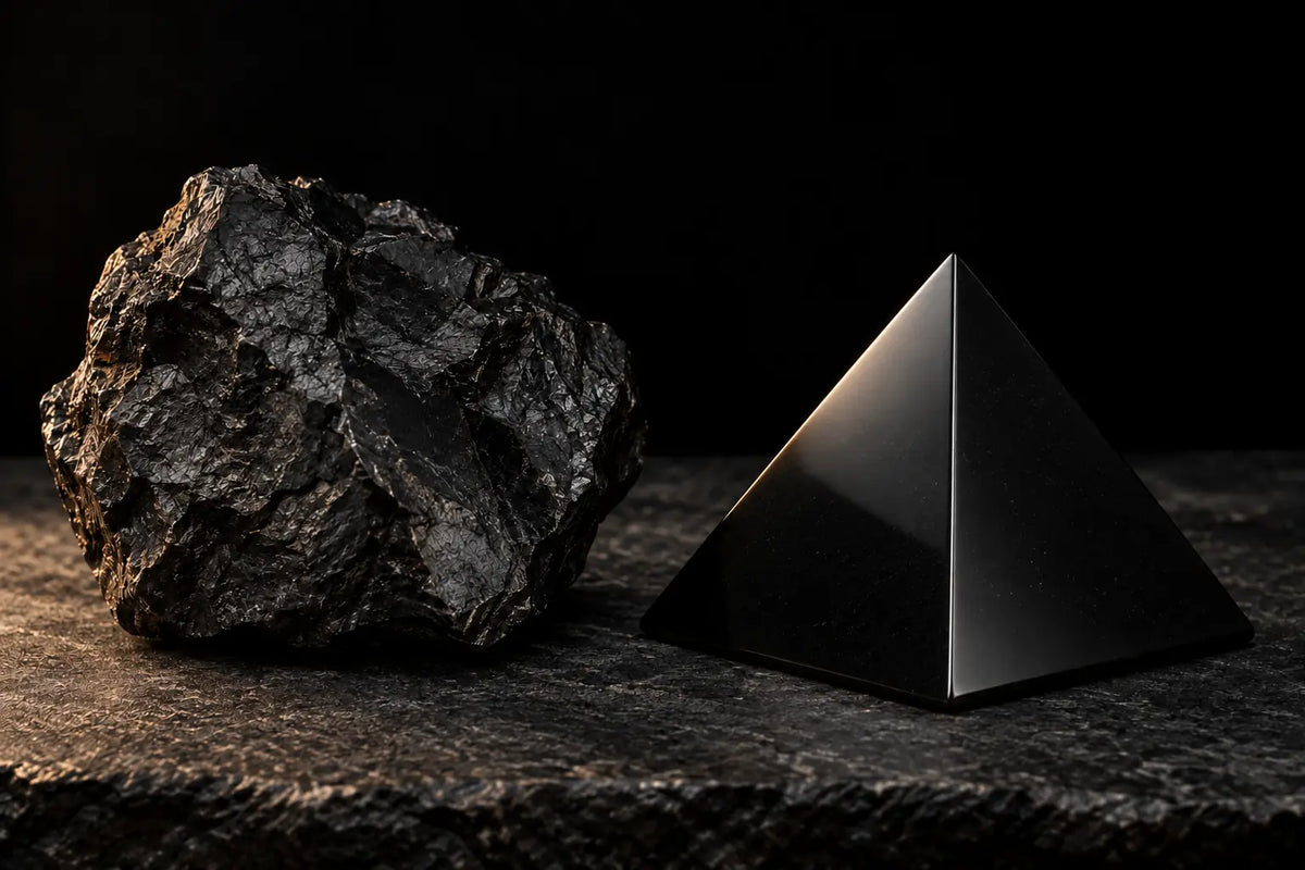Un frammento grezzo di shungite accanto a una piramide lucidata